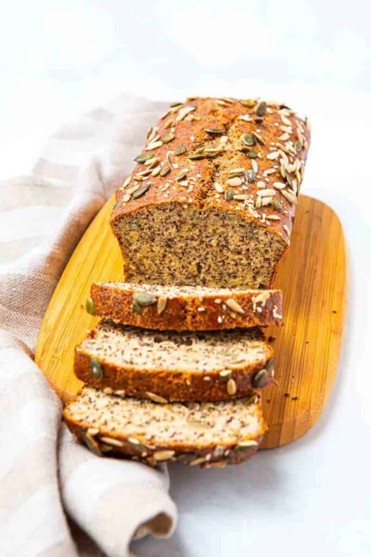 Loaf of bread on a wooden plate with three pieces cut up in front of the picture. 