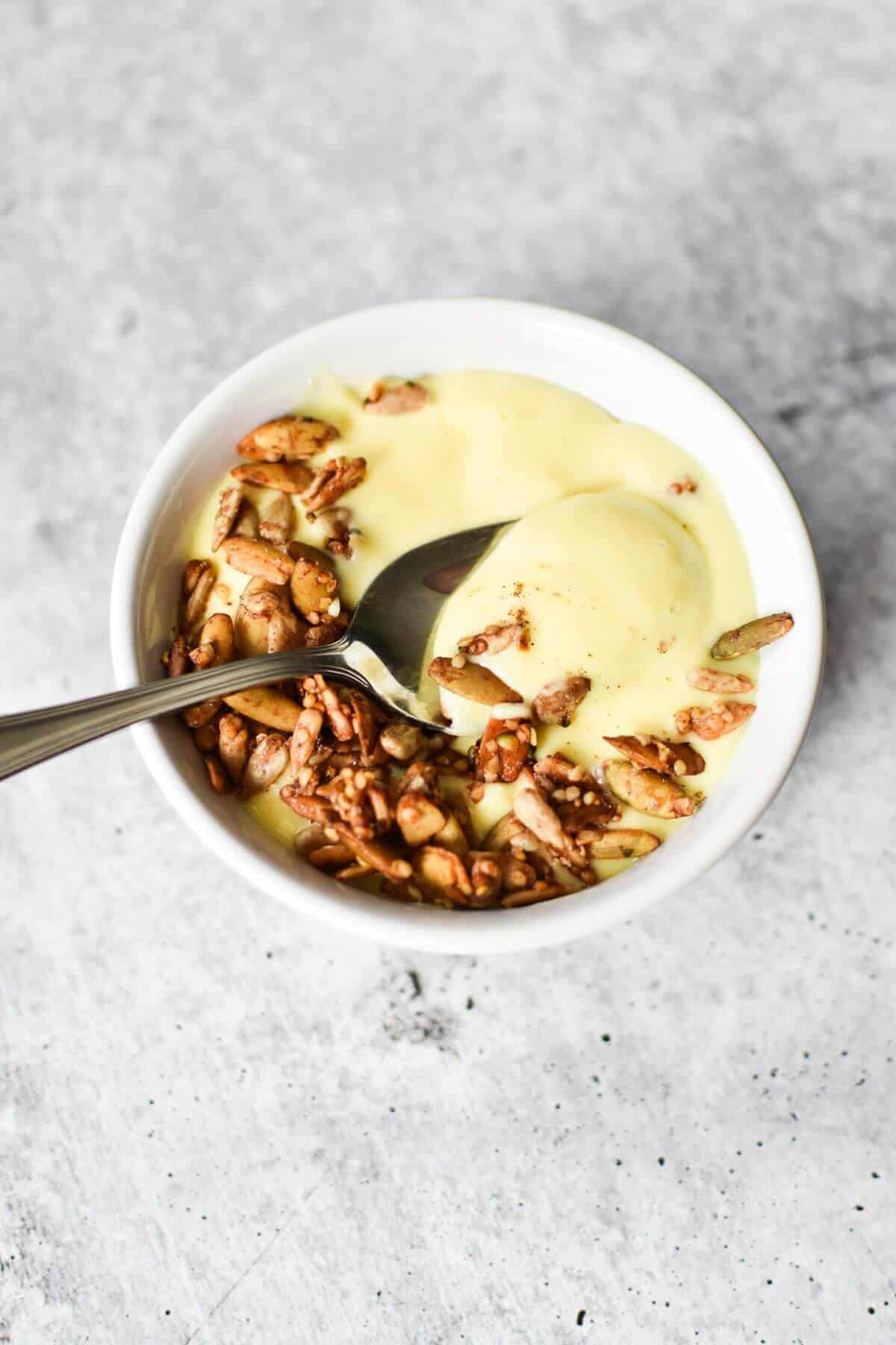 White bowl with bright yellow smoothie and seeds on top. 