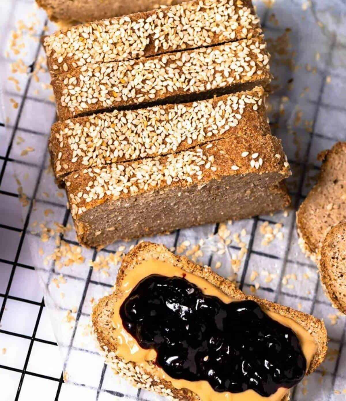 Sliced loaf of bread and one slice spread with peanut butter and jam. 