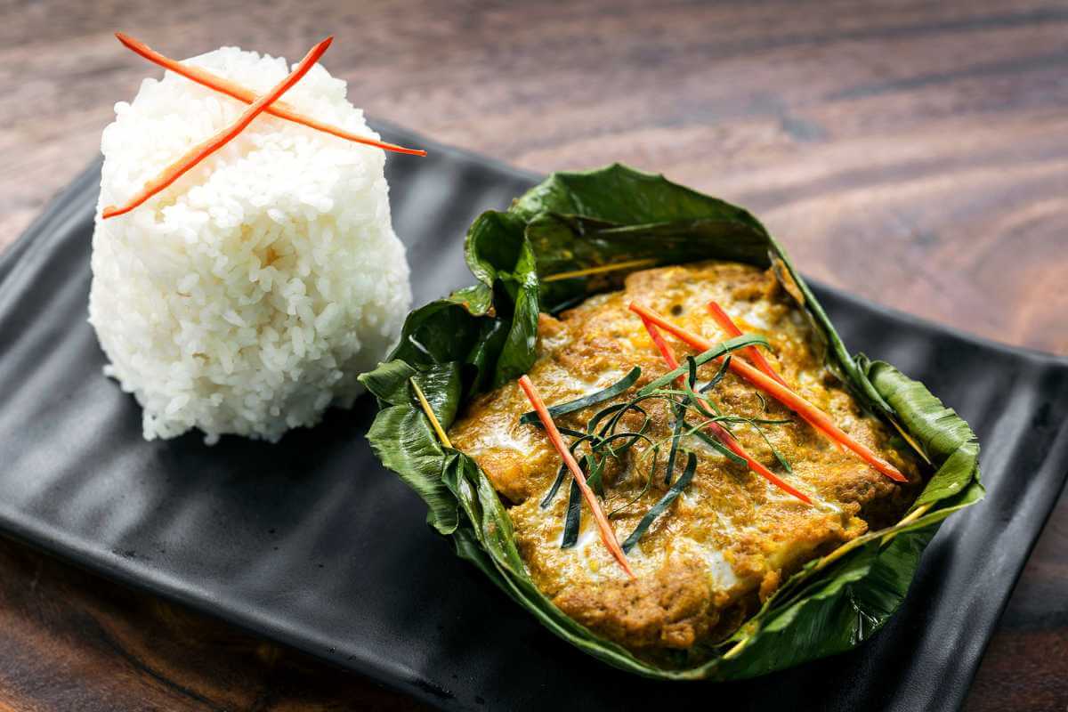 Amok trey in a banana leaf next to a pile of white rice