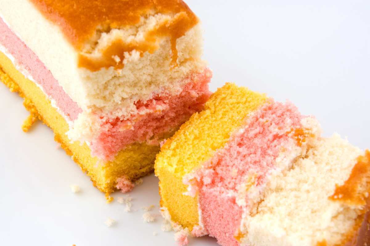 A couple pieces of angel cake, cut open showing the pink and yellow layers. A very tasty food that starts with A