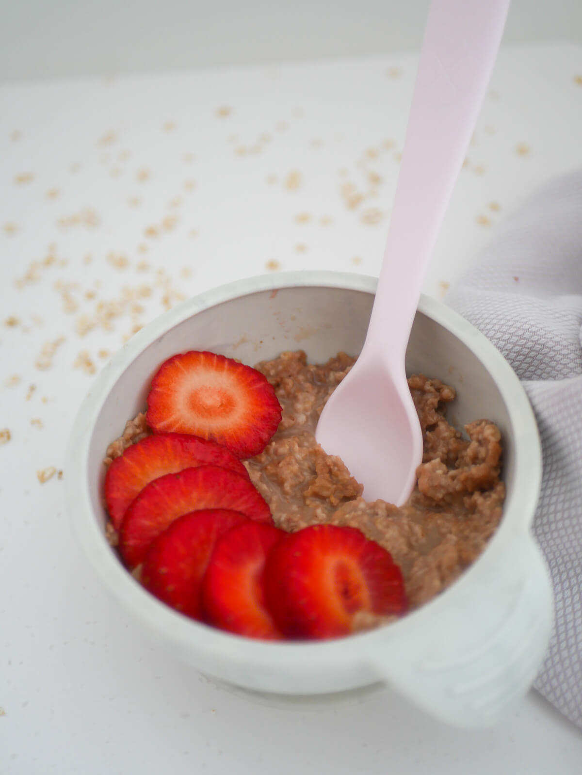 Hazelnut oatmeal cereal in a silicone bowl with a pink spoon 