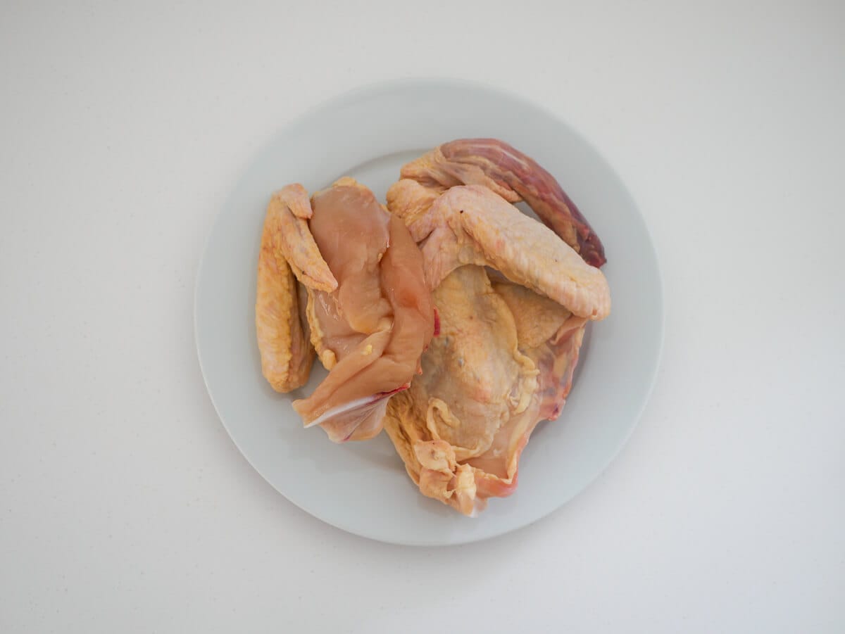 2 raw chicken quarters on a white plate 