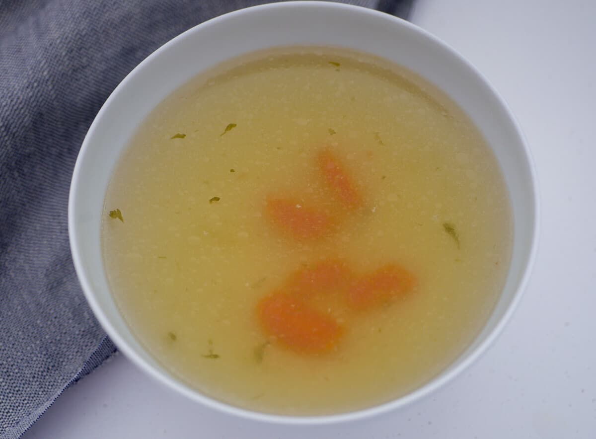 chicken soup with some carrots floating 