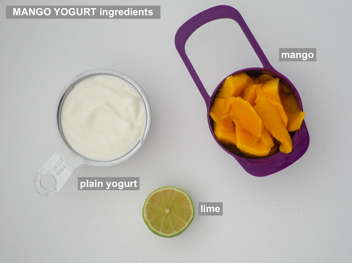 ingredients for yogurt with mango on white background - plain yogurt, mango, halved lime