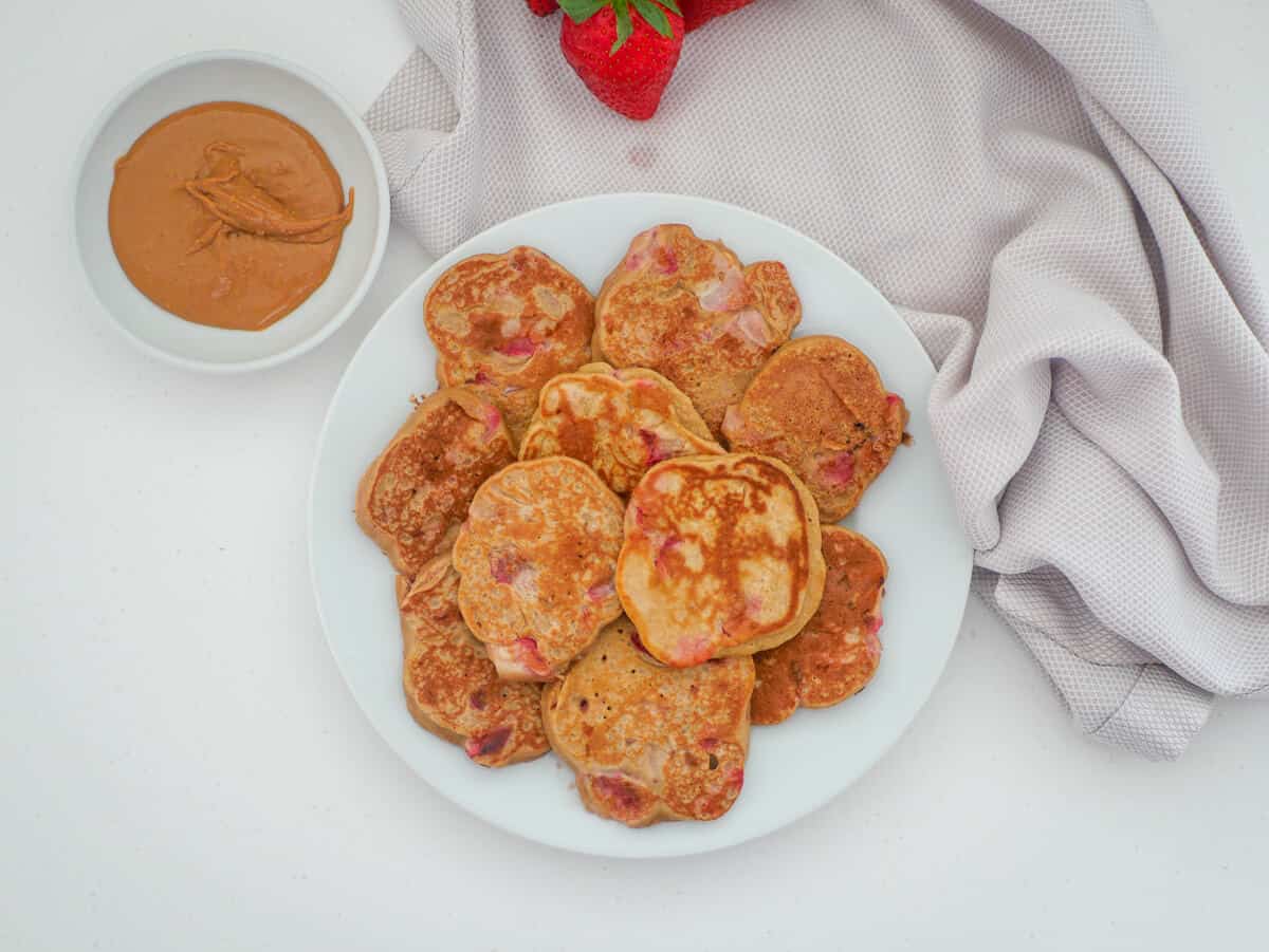 strawberry pancakes on a plate with peanut butter on the side