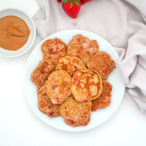 Strawberry pancakes on a plate with peanut butter on the side
