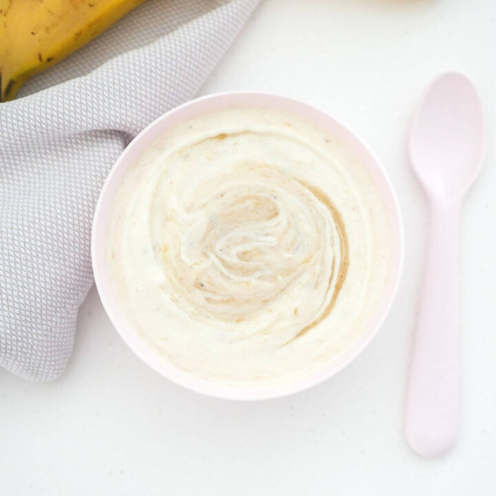 banana yogurt in a pink bowl with a spoon next to it