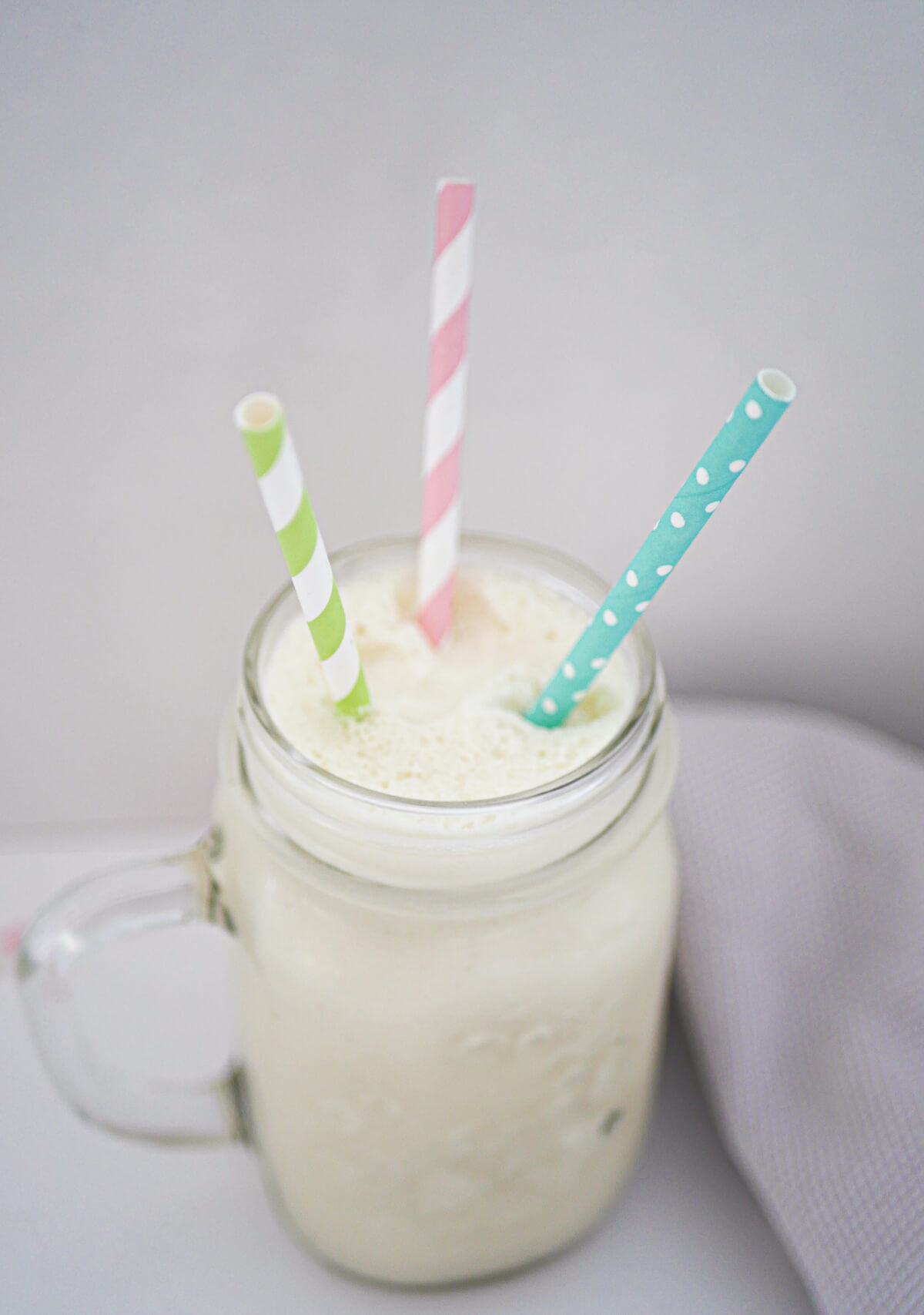 glass with coconut milkshake and three straws