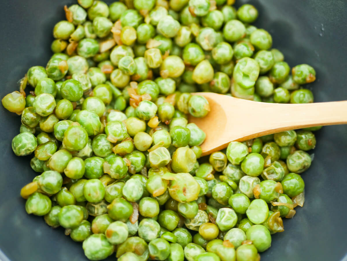 close up of cooked frozen peas in a black bowl