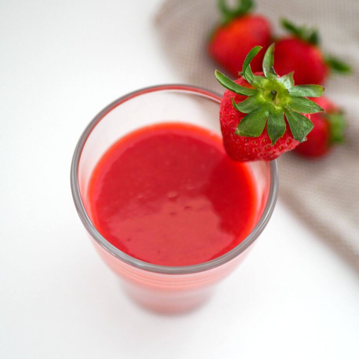 partial birdseye view of strawberry juice in a glass