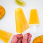 hand holding mango popsicles