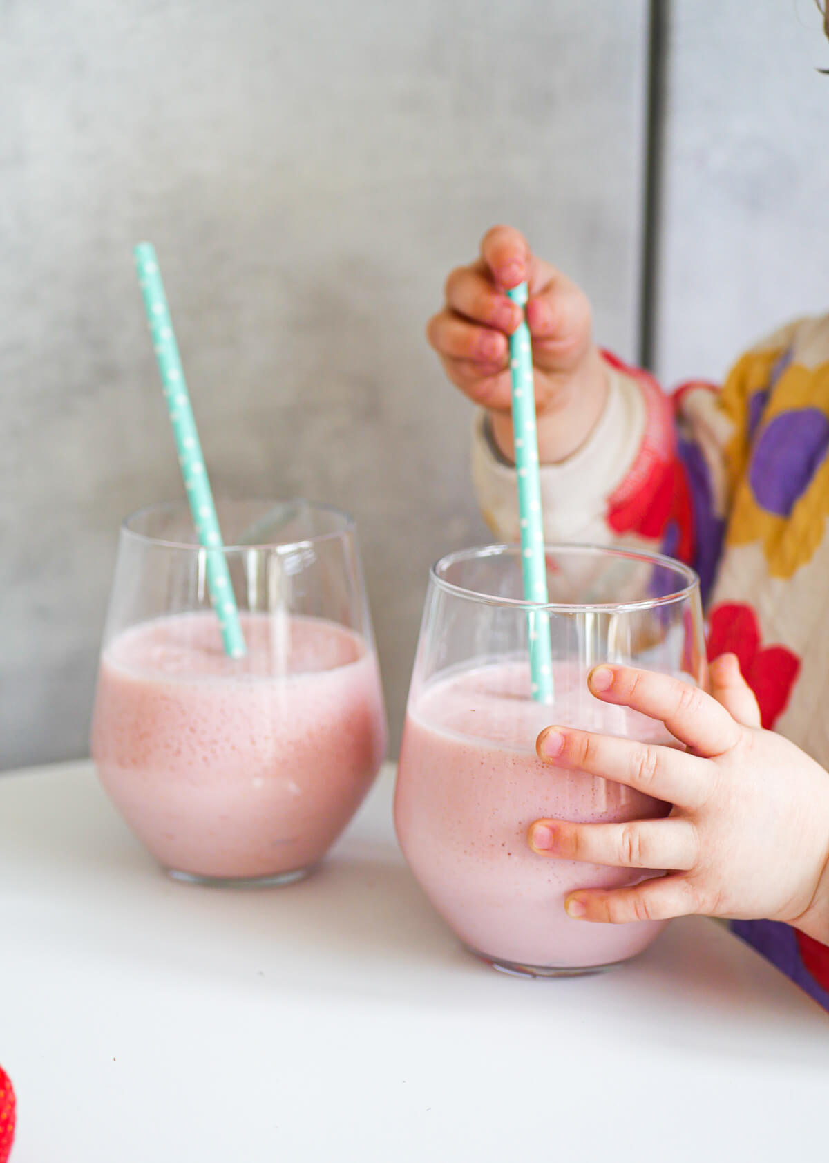 toddler holding glass with milk and another glass in the backrgound 