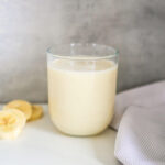 banana milk in a glass with banana slices next to it