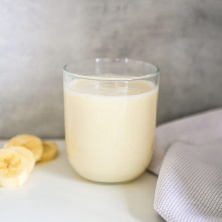 banana milk in a glass with banana slices next to it