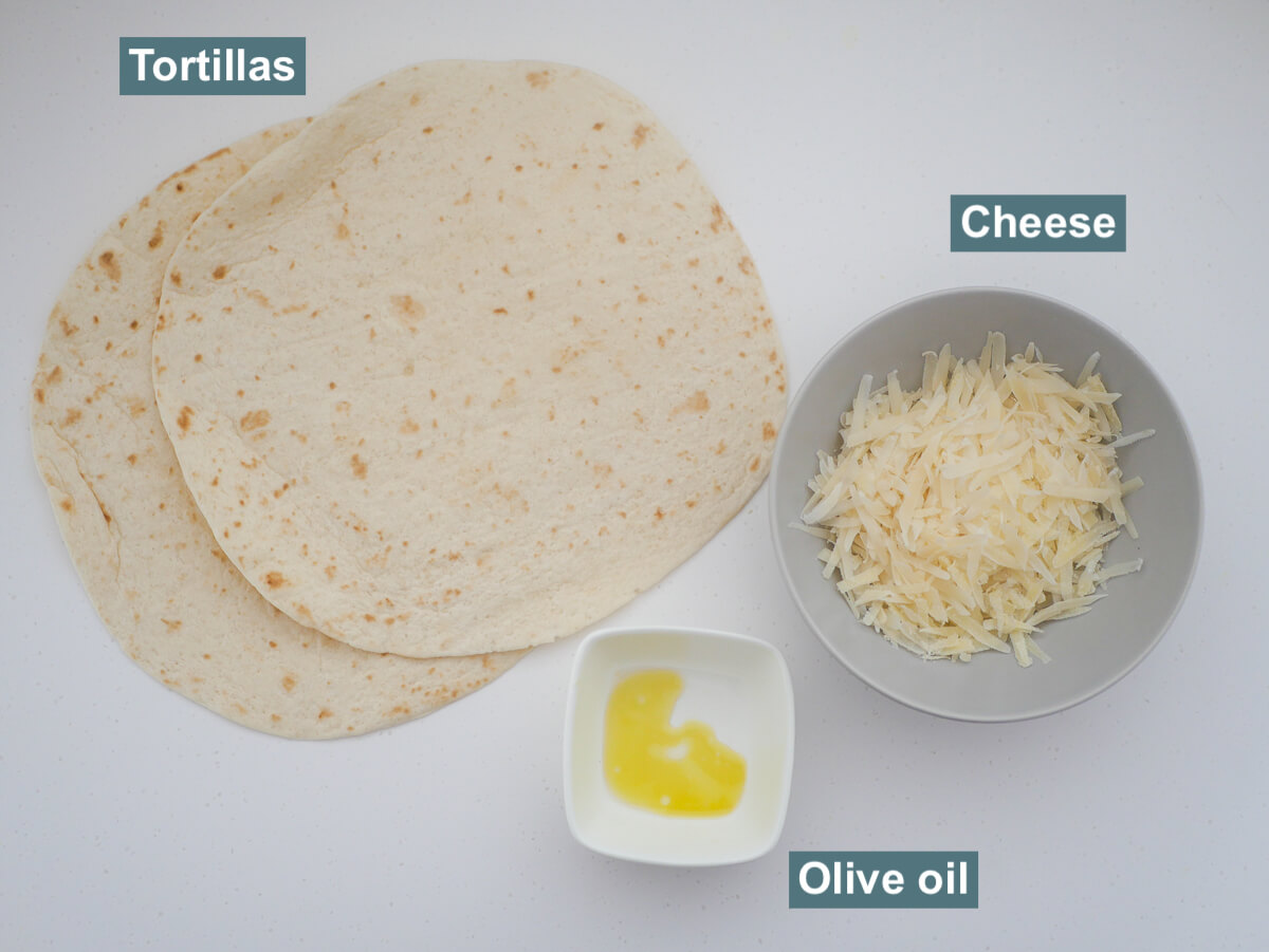 ingredients on white background - tortilla, a bowl of cheese and olive oil