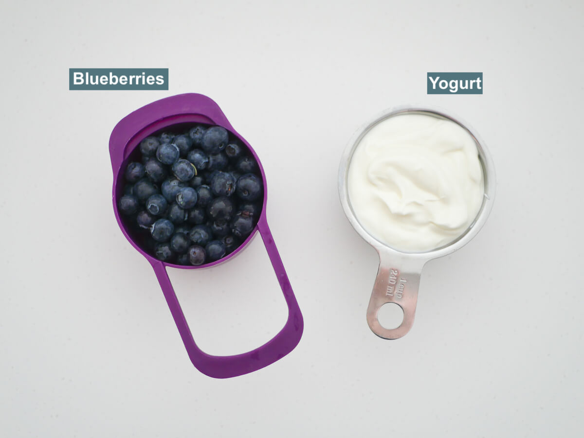 ingredients in measuring cups on white background - blueberries and yogurt