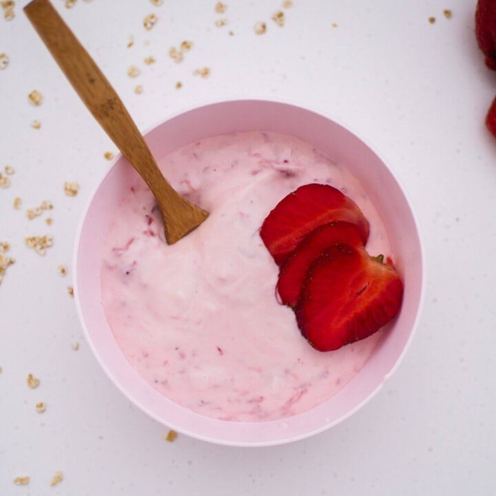 strawberry yogurt in a pink bowl with cut up strawberries