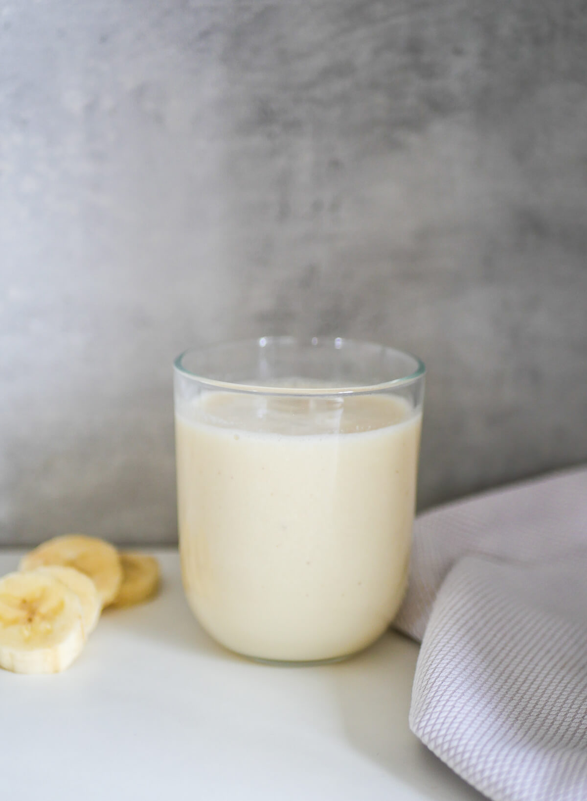 banana milk in a glass with banana slices next to it