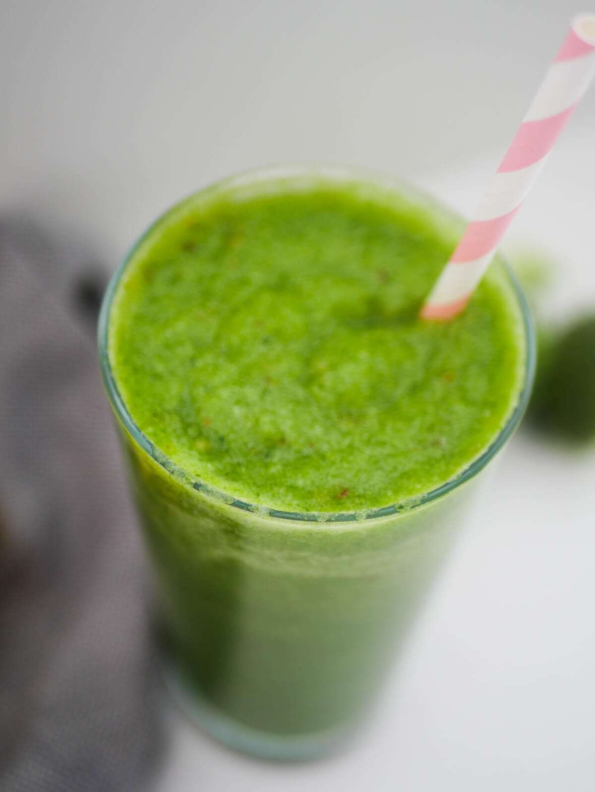 green smoothie in a glass with pink straw
