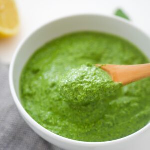 green pasta sauce with wooden spoon dipped in