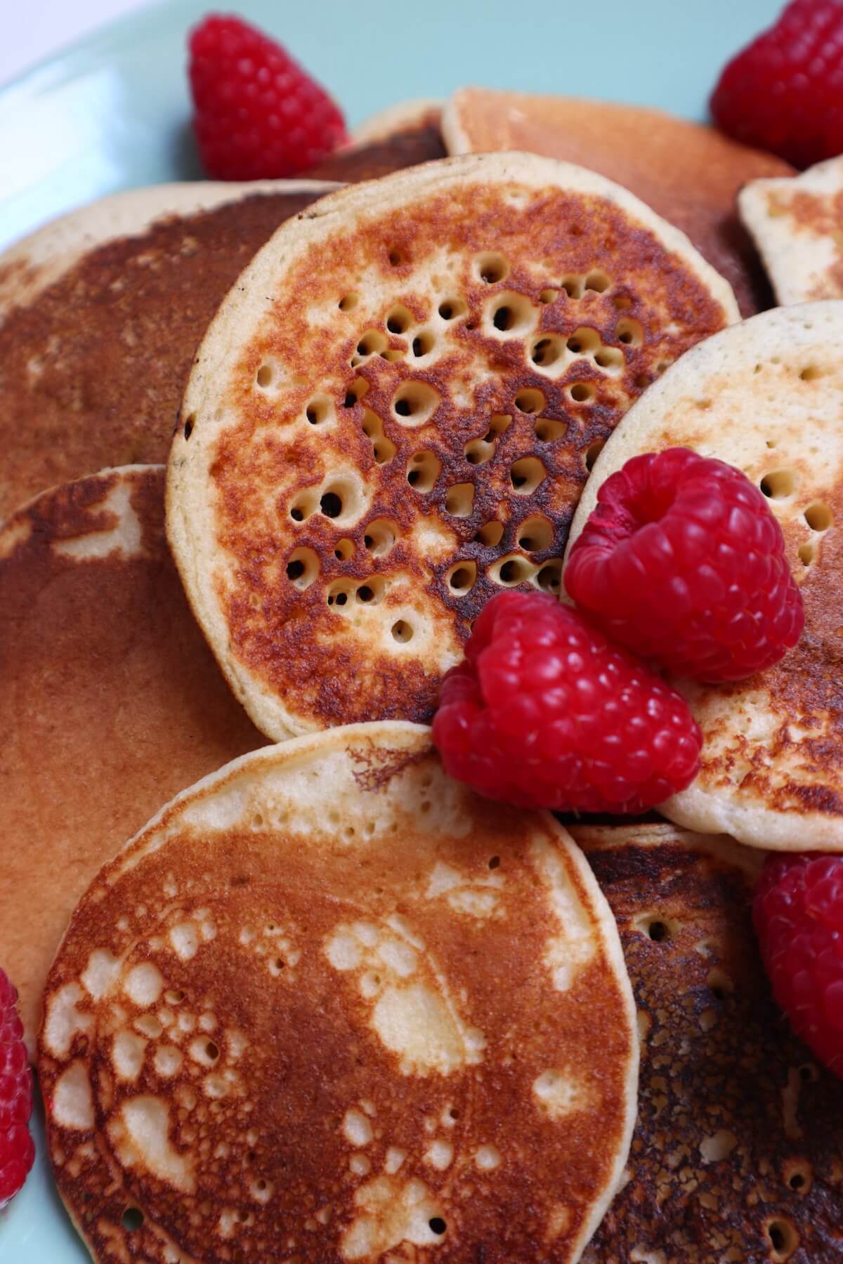 very close up shot or pancakes topped with raspberries