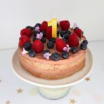 full frontal image of cake with berries and a number 1 candle