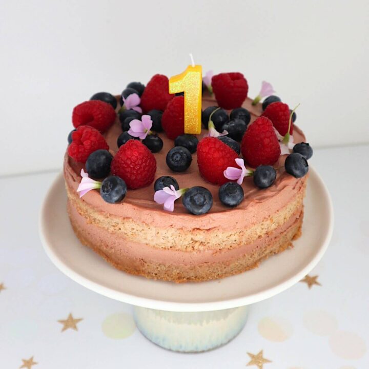 full frontal image of cake with berries and a number 1 candle