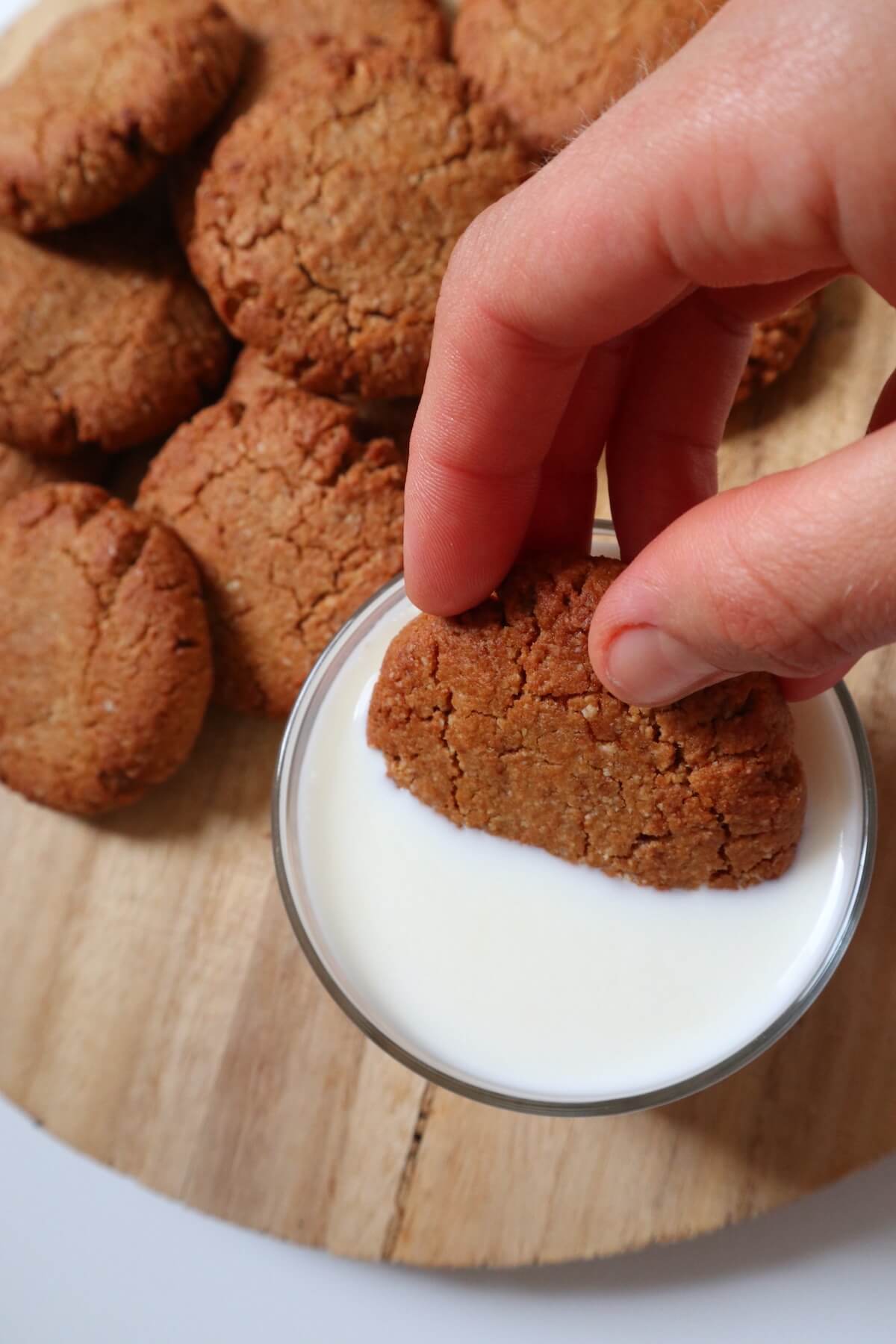 hand dipping cookie in milk
