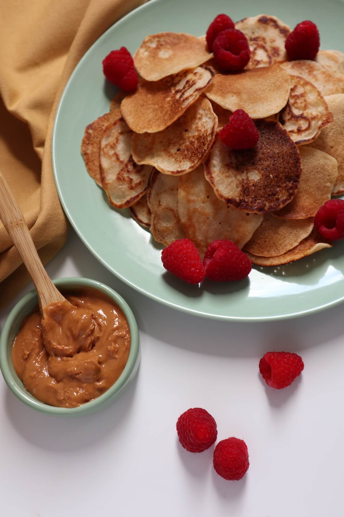 fluffly eggless pancakes on a plate with peanut butter in a bowl