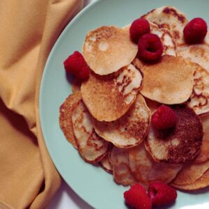 close up with delicious looking brownish pancakes topped with raspberries