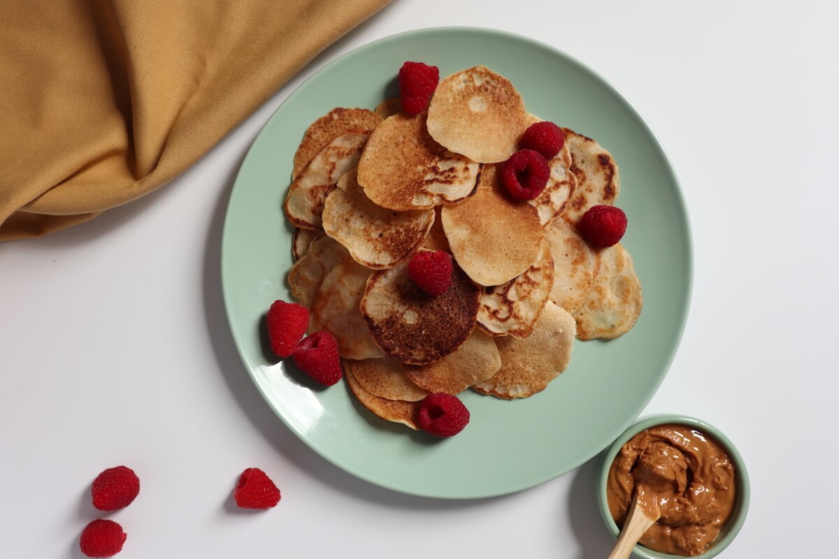 pancakes on a blue plate topped with raspberries