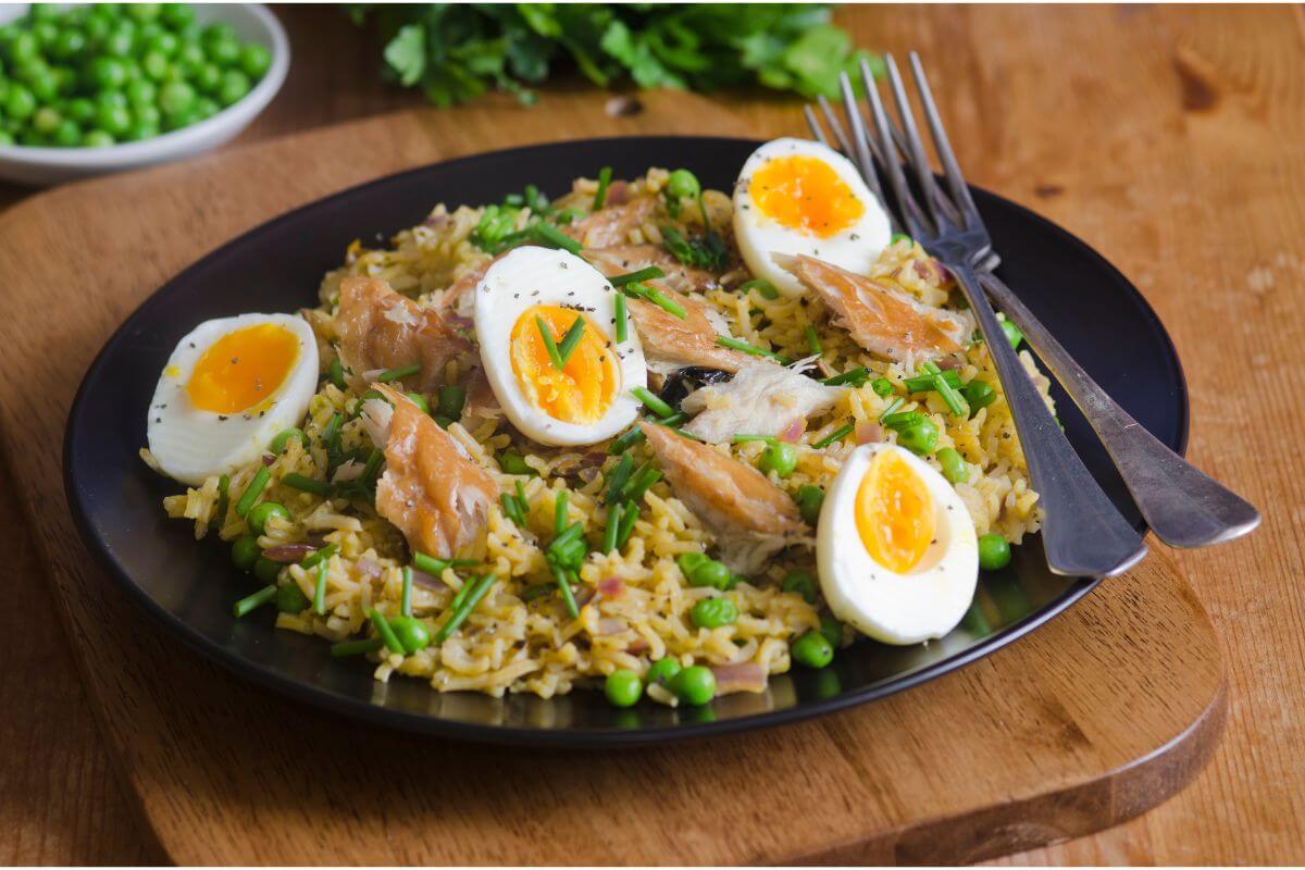 A plate of kedgeree, shown with 4 half hard-boiled eggs, flaked fish, rice and peas
