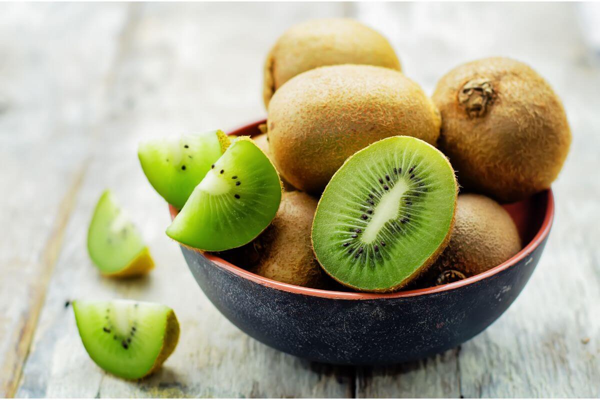 A bowl of kiwis, some cut in half or quarters