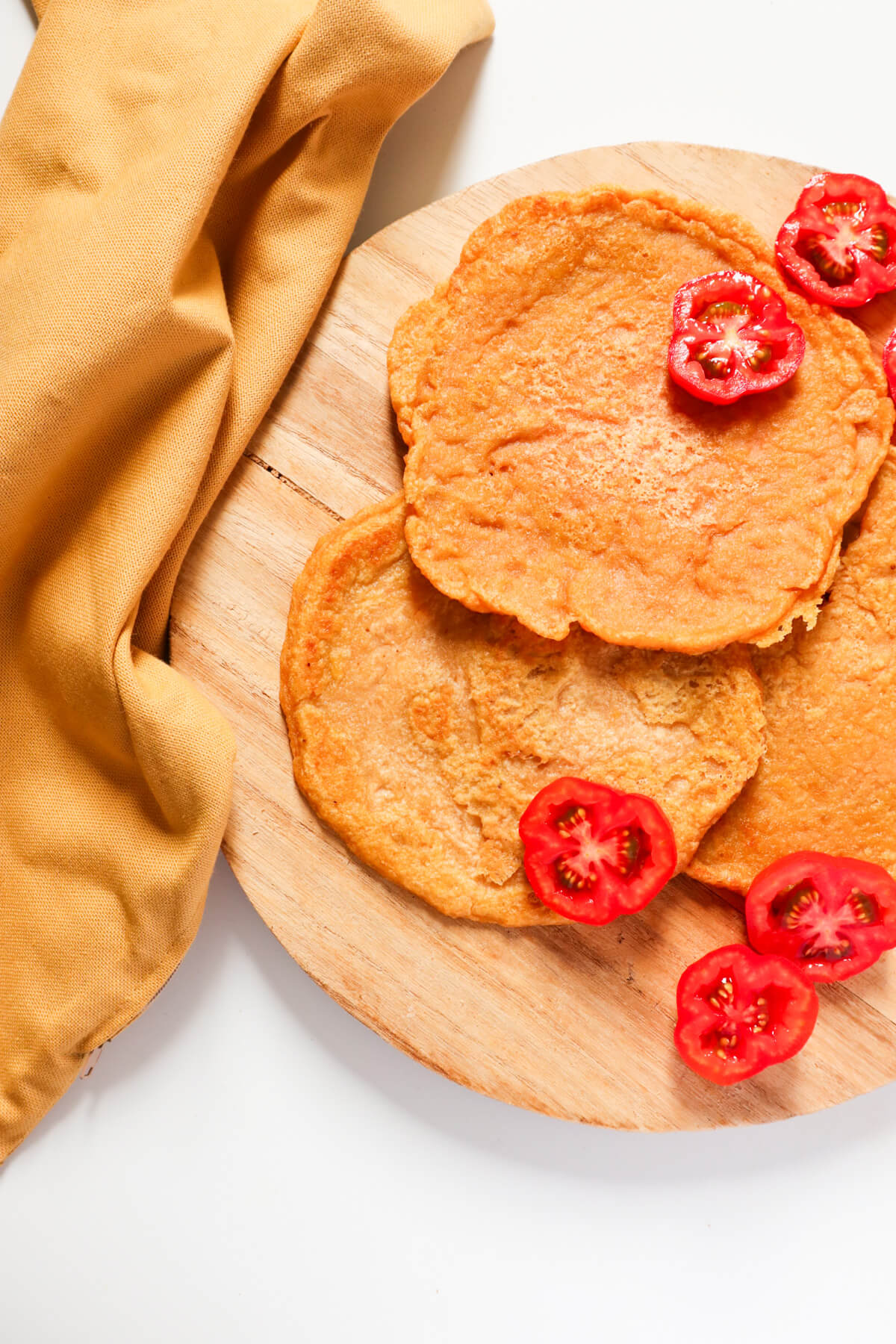 Red lentil wraps with cut up tomatoes and brown kitchen towel on the side. 