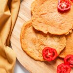 Red lentil wraps with cut up tomatoes and brown kitchen towel on the side.