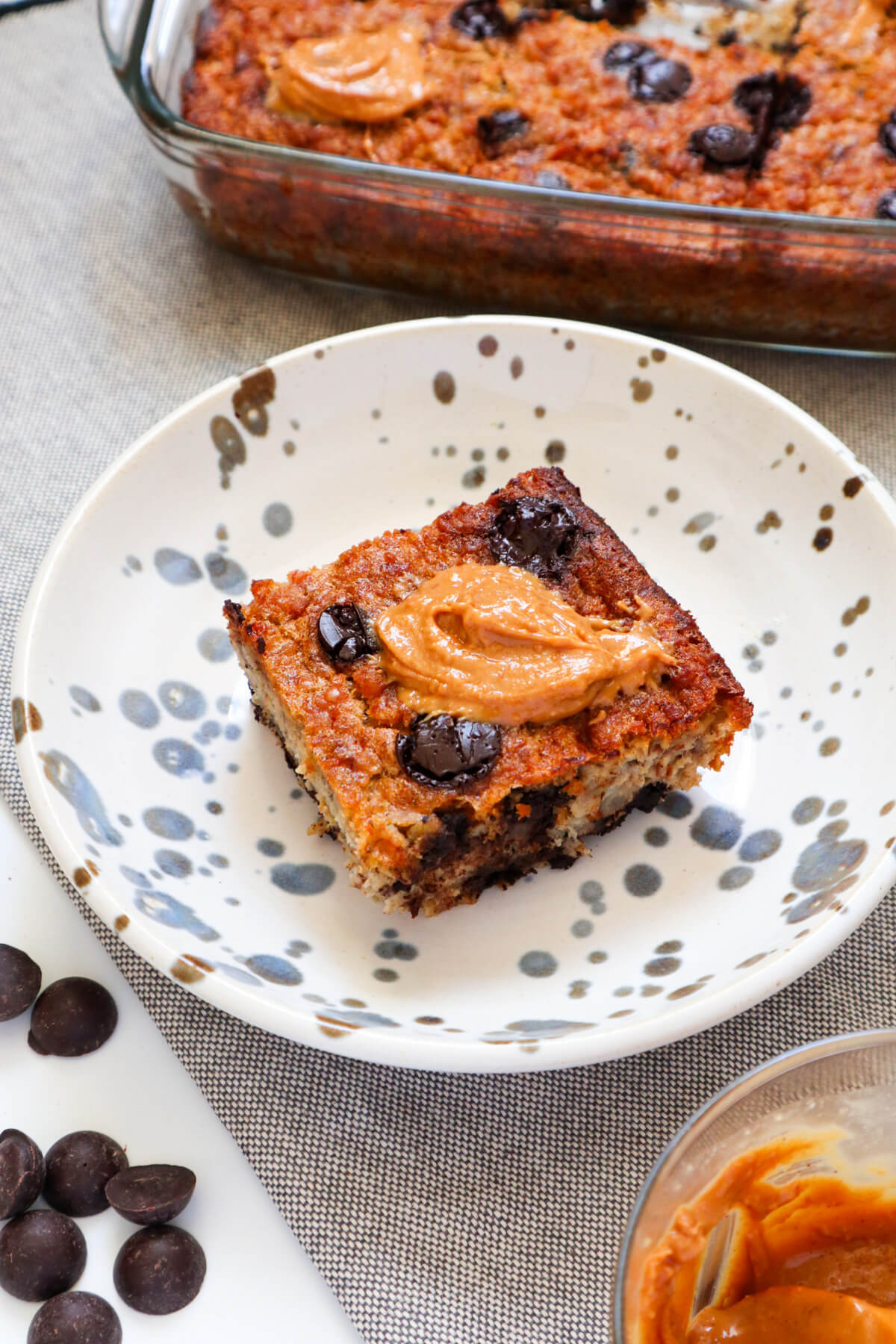 Slice of baked oatmeal topped with chocolate chips and peanut butter.