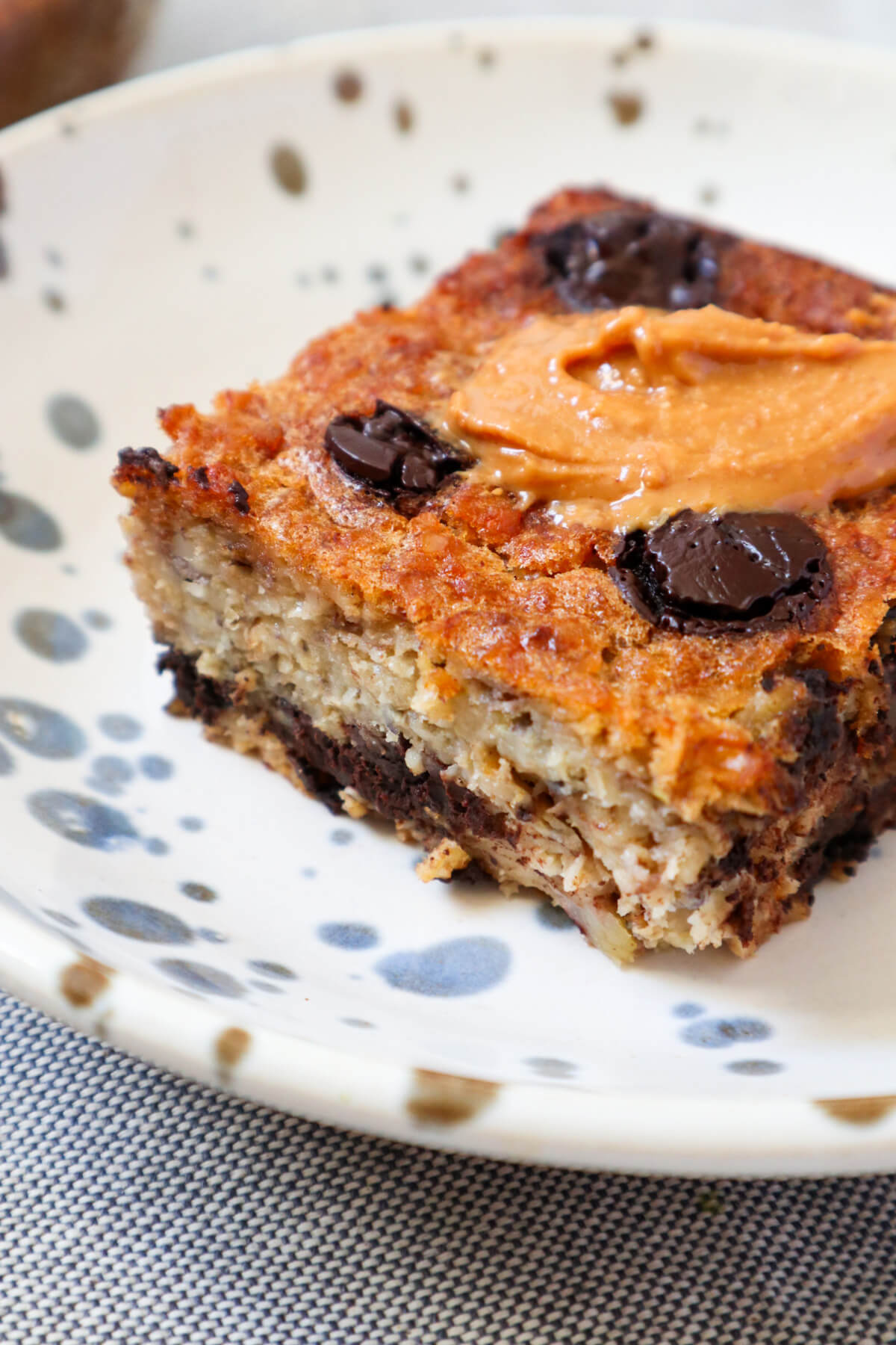 Slice of baked oatmeal topped with chocolate chips and peanut butter.