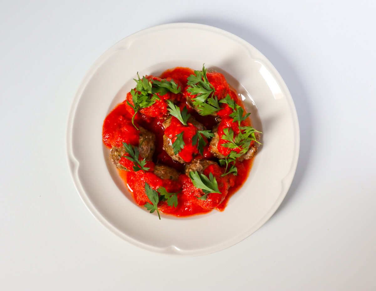 meatballs for toddler covered with marinara on a hwite plate.