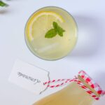 Lemon juice in a glass with a bottle of lemon juice on the side.