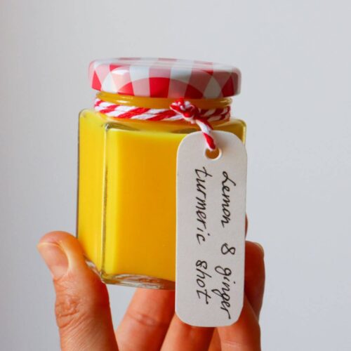 hand holding the ginger turmeric shot in a jar with a label