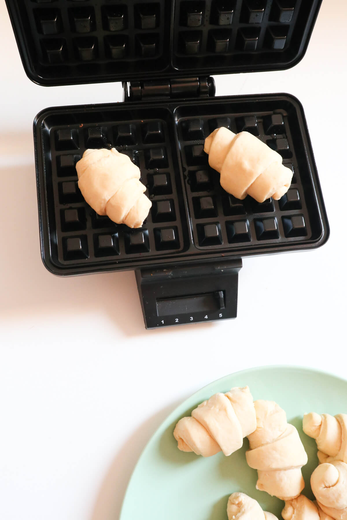 Placing little croissants into a waffle iron.