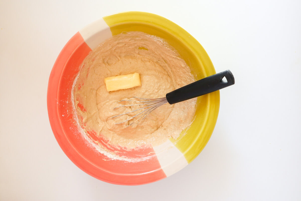 Butter added to the dry ingredients in a bowl. 
