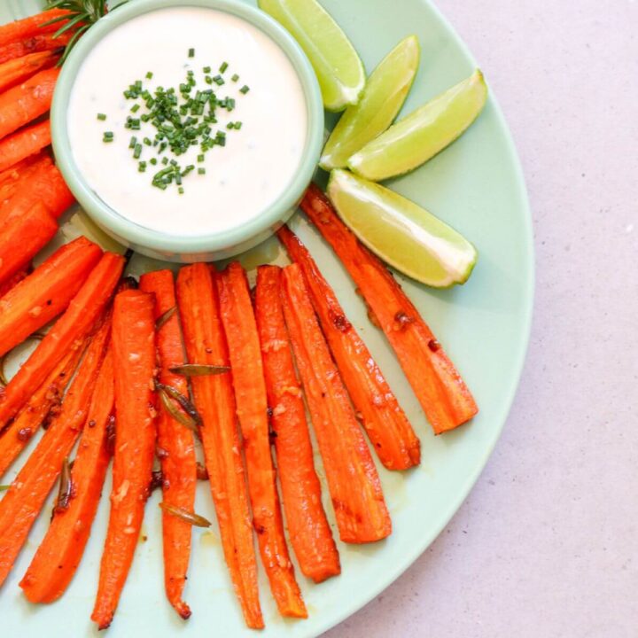 carrot fries on plate with some white dip and lime wedges