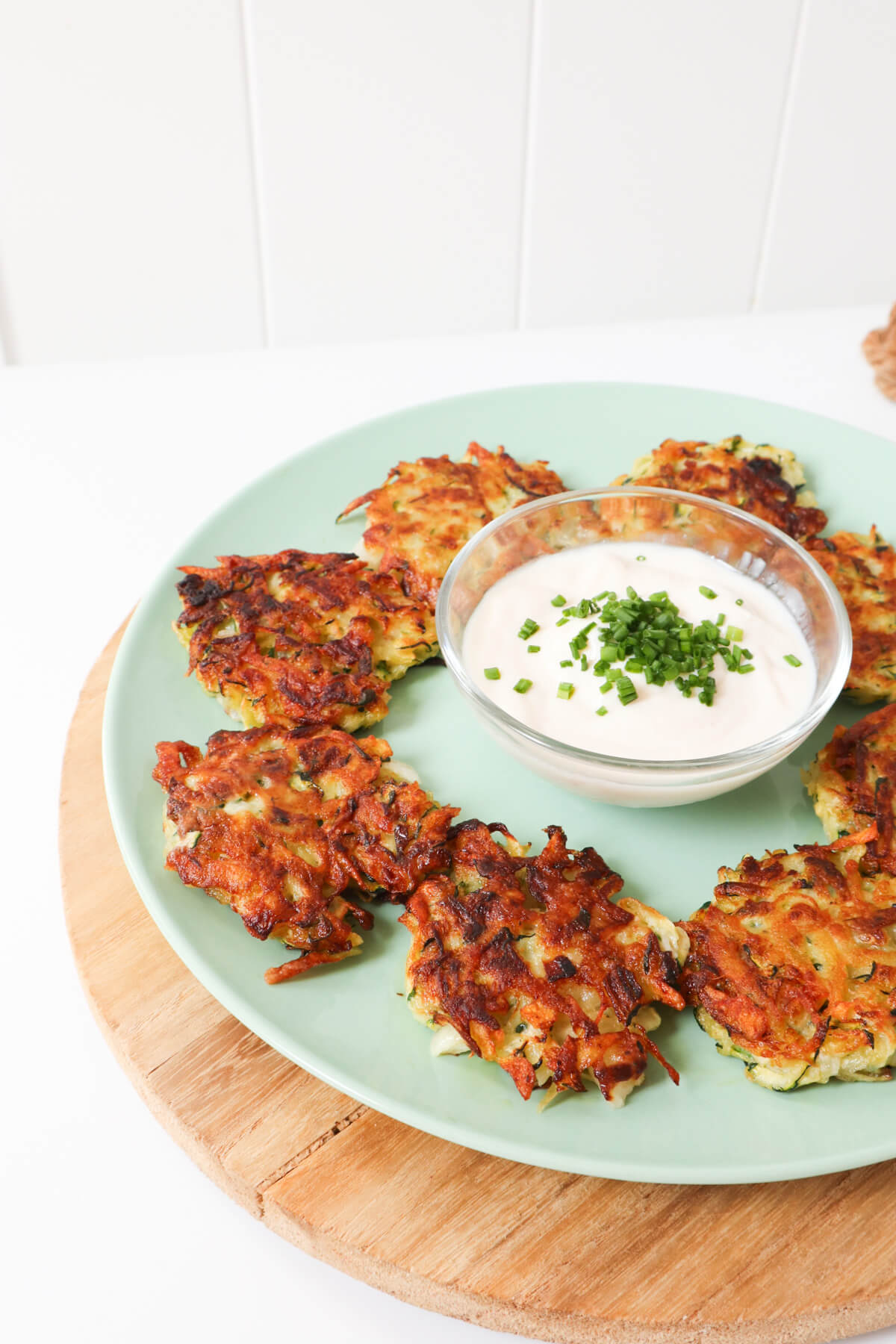 zucchini fritters on a blue plate with a white dip in the middle