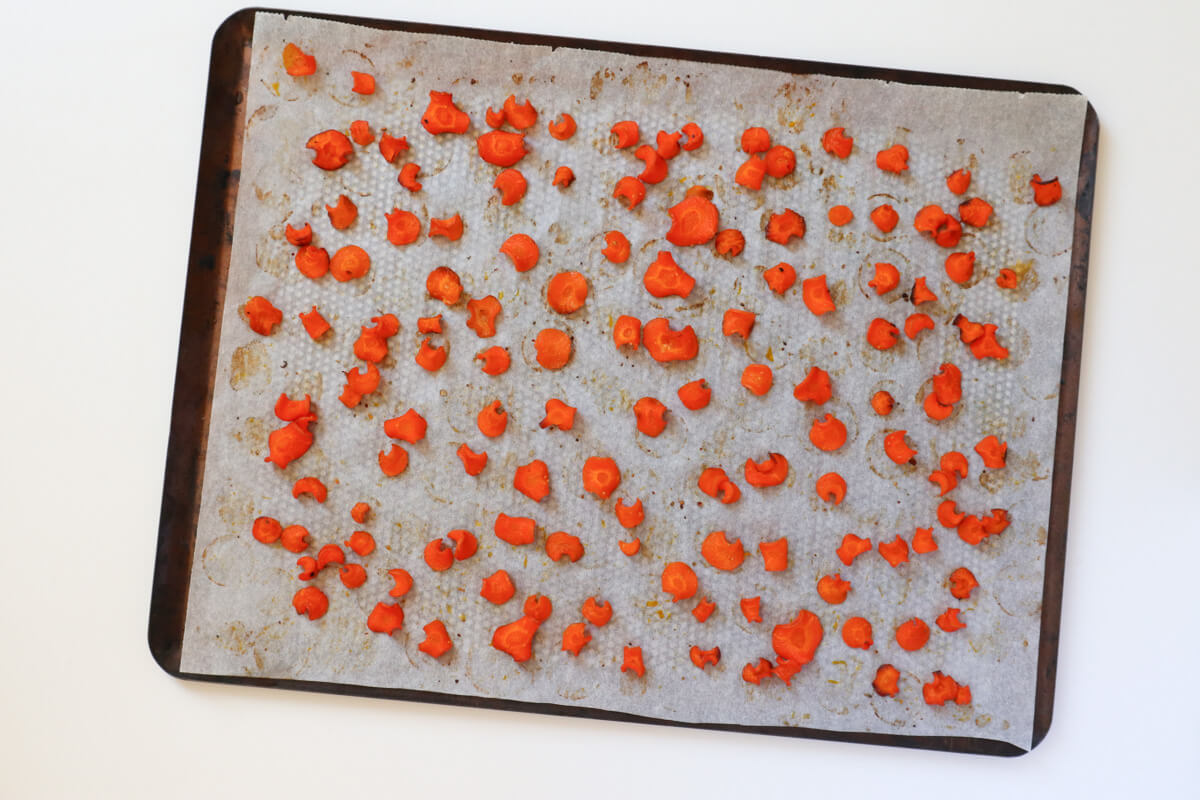 Baked carrot chips on baking tray with parchment paper.