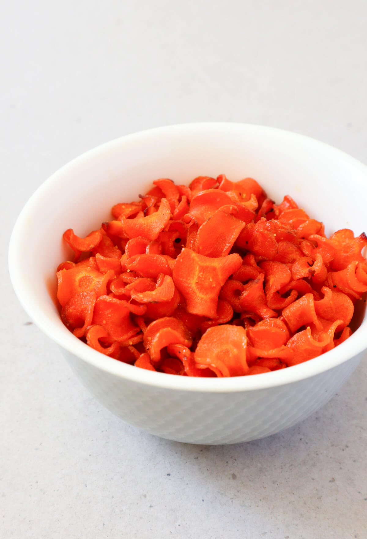 Carrot chips in a white bowl. 