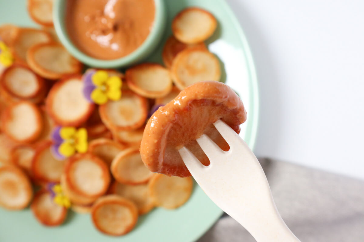 close up of a peanut butter coated mini pancake on a fork