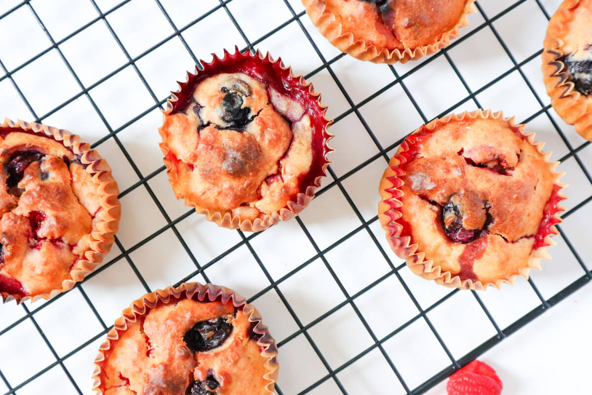 close up of multiple berry muffins on a cookie sheet 