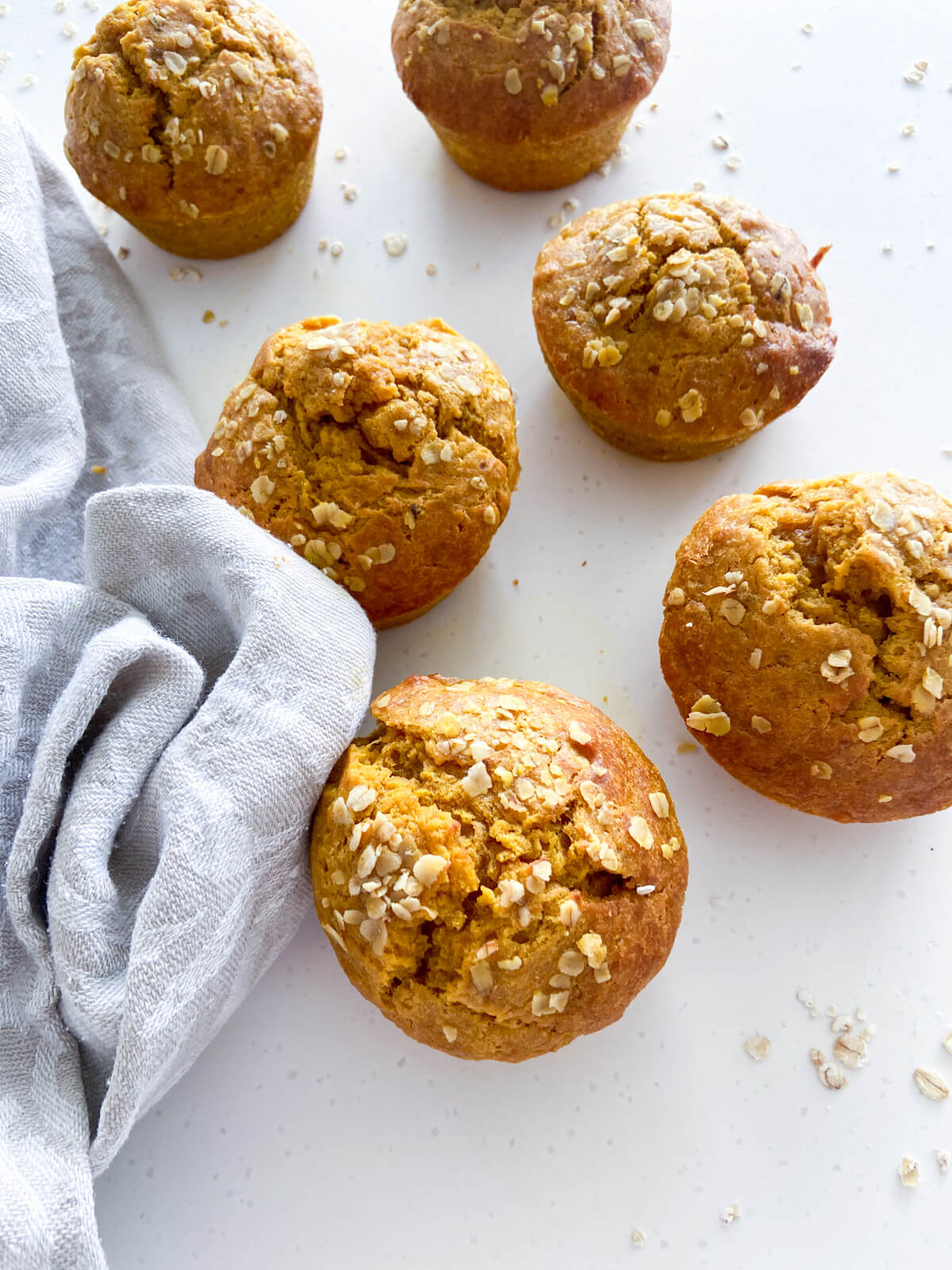 6 banana pumpkin muffins with tablecloth on the right.